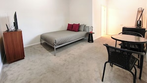 Una habitación pequeña y poco amoblada con una cama, una mesita y una silla.