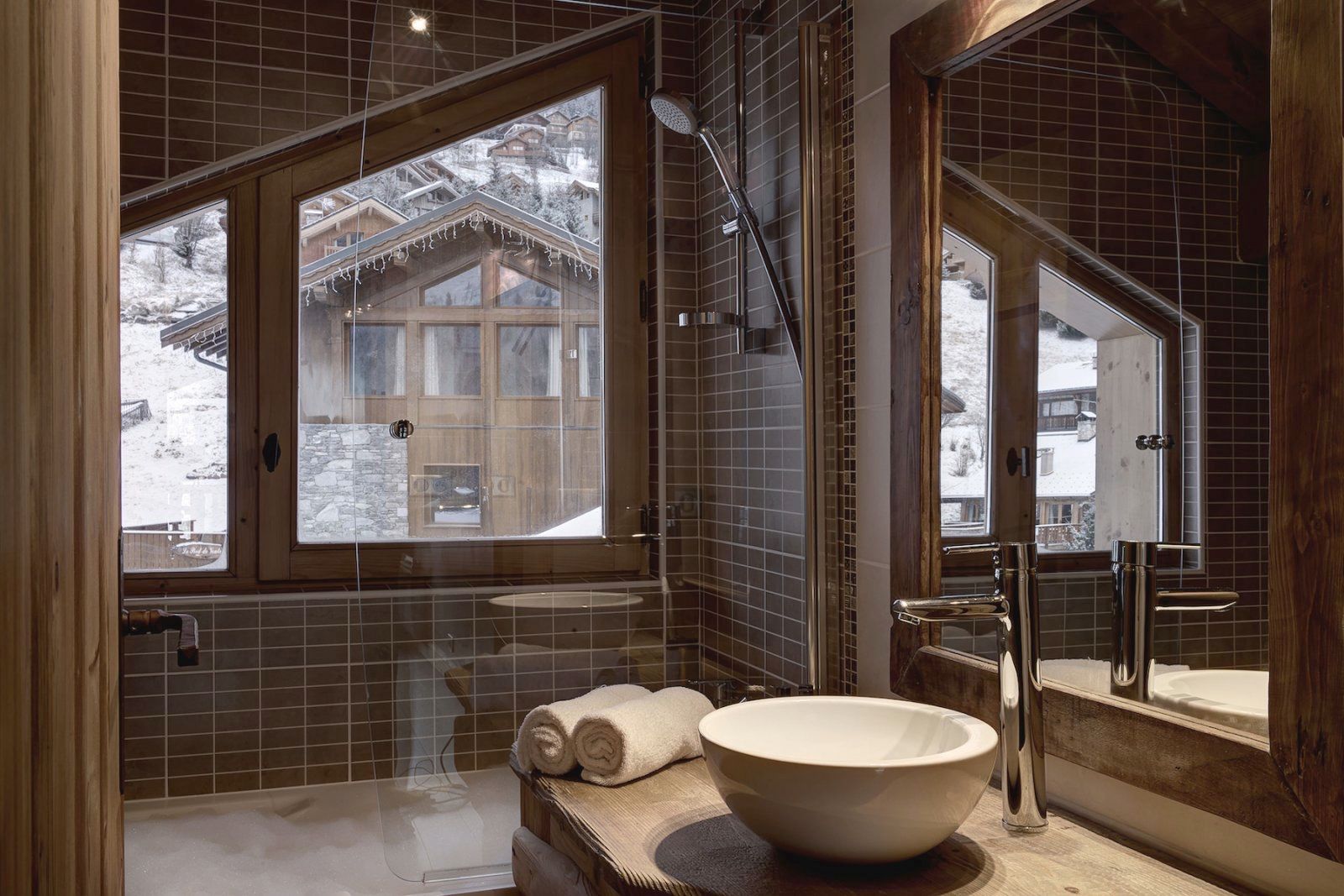 A bathroom with a large window, a bathtub, a sink, and a mirror.
