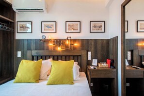 A hotel room with a bed, bedside table, and a mirror. There are framed pictures on the wall, a clock, and a thermostat. - Captain Stam Suites Athens - CityStudio (Athina)