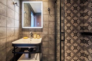 A modern bathroom with a large mirror, a sink, and a shower area. - Captain Stam Suites Athens - CityStudio (Athina)