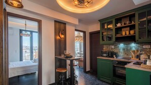 A modern kitchen with green cabinets, a dining area with a table and chairs, and a bar area with stools. - Captain Stam Suites Athens - FamilyApartment (Athina)