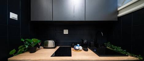 A modern kitchen with a black countertop, stainless steel appliances, and a black backsplash.