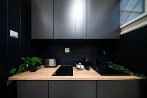 Eine moderne Küche mit schwarzer Arbeitsplatte, Edelstahlgeräten und einer schwarzen Spritzschutzwand.