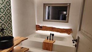 A bathroom with a wooden vanity, a black basin, and a wooden tray holding black utensils. - Masseria Camerlengo (CASTELLANA GROTTE)