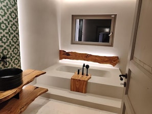 A bathroom with a wooden vanity, a black basin, and a wooden tray holding black utensils. - Masseria Camerlengo (CASTELLANA GROTTE)