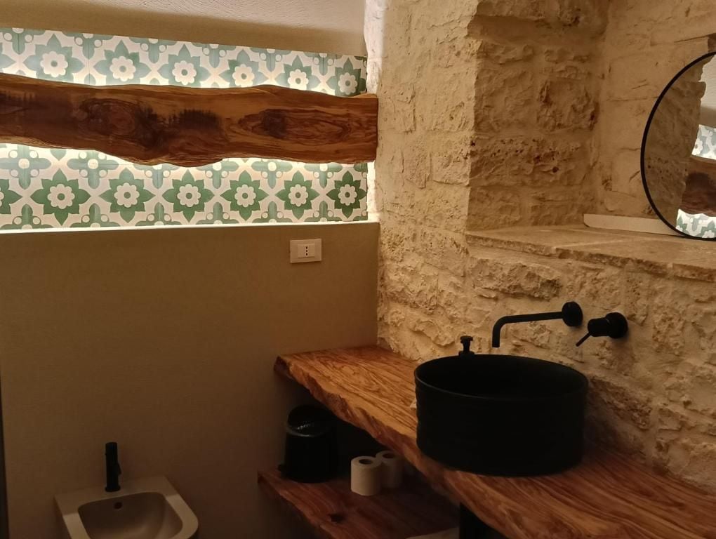 A bathroom with a wooden vanity, a black sink, and a mirror.