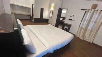 Habitación de hotel con cama, escritorio, silla, armario y baño.