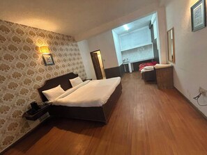 A hotel room with a large bed, a bedside table, a lamp, a wardrobe, and a bathroom visible in the background. - Hotel Solpine Retreat Manali (Manali)