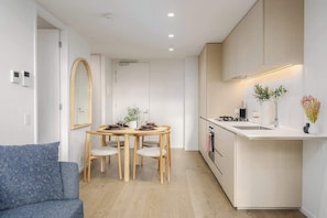 A compact kitchen with a dining area, wooden furniture, and a modern design. - LaneStay - 1BR Southbank Skyline Stay, Pool & Gym (Southbank)