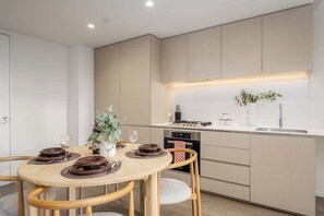 Eine moderne Küche mit Essbereich, ausgestattet mit einem runden Holztisch, Stühlen und einem Einbauofen.