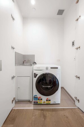 Ein kleiner Waschraum mit einer Waschmaschine mit Frontlader, einem Spülbecken und einem Schrank.