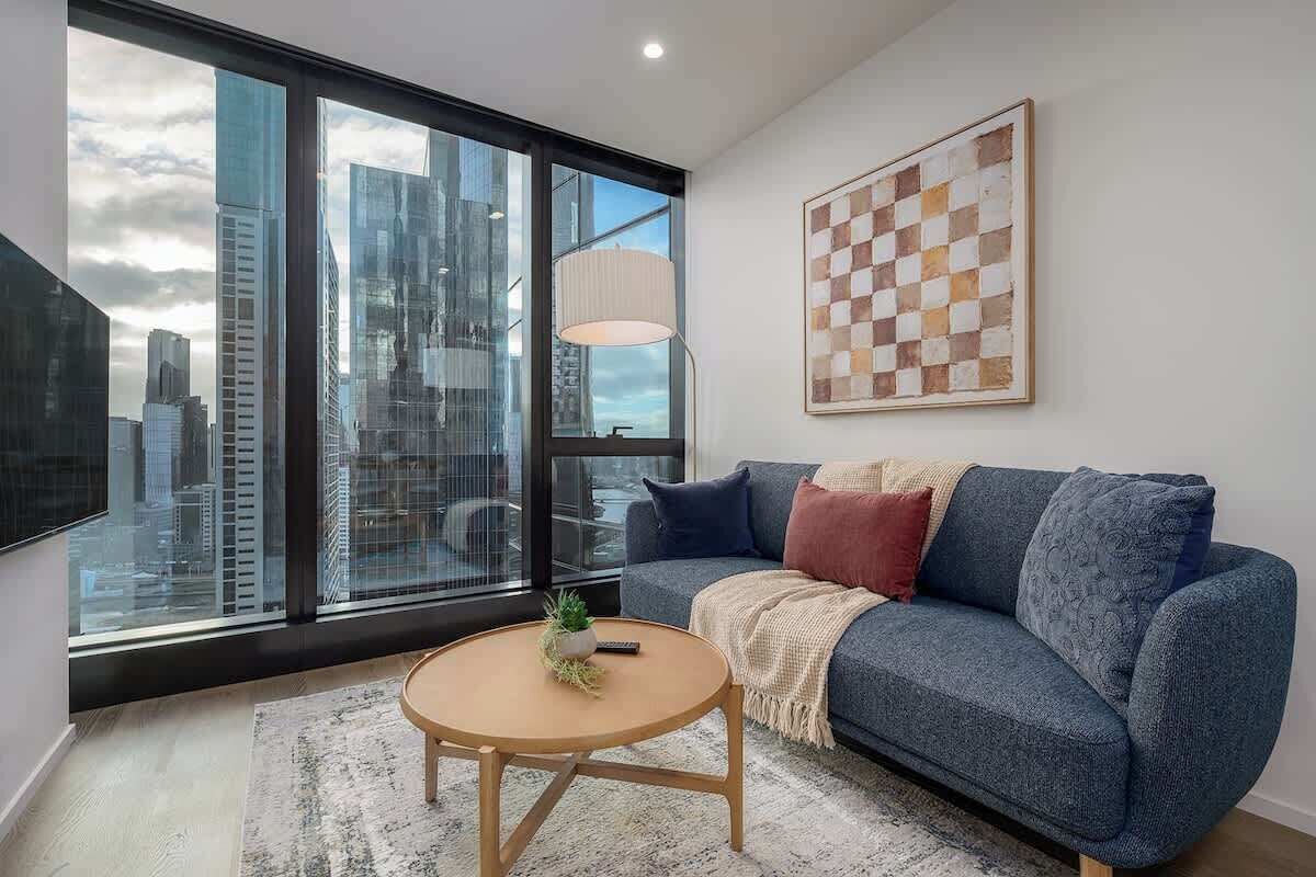Un salon moderne avec une grande fenêtre, un canapé, une table basse et une vue sur la ville.