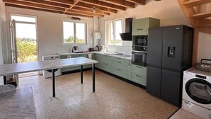 A kitchen with a table, cabinets, a refrigerator, and a washing machine.