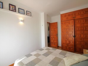 A bedroom with a bed, a wardrobe, and a shelf with framed pictures. - Bright apartment by the beach - 4 guests (Llançà)