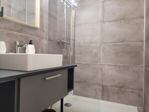 Ein modernes Badezimmer mit Waschbecken, Spiegel und Duschkabine.