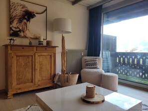 Una sala acogedora con un aparador de madera, una lámpara, un sillón y una mesa con un adorno.