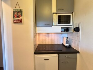 Eine kleine Küche mit einer Mikrowelle, einem kleinen Kühlschrank und einer Kaffeemaschine auf der Arbeitsfläche.
