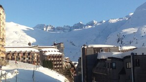 A snow-covered mountain with a ski resort in the foreground, featuring multi-story buildings with balconies and a ski lift visible. - Comfortable apartment with south-facing balcony - 4 guests (Avoriaz)