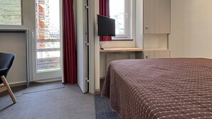 A hotel room with a bed, a desk with a computer, a chair, and a TV. - Comfortable apartment with south-facing balcony - 4 guests (Avoriaz)