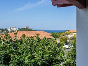 A coastal view with a building on a hill, a clear sky, and a parked car. - Apartment with shared pool, parking - 4 guests (Biarritz)