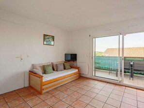 A room with a sofa, a television, and a sliding glass door leading to an outdoor area. - Apartment with shared pool, parking - 4 guests (Biarritz)