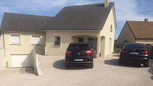 Um bairro residencial com dois carros estacionados na entrada da casa.