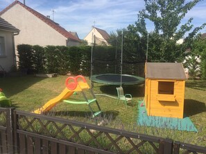 Ein Garten mit Trampolin, Spielhaus und einer kleinen Holzhütte zum Spielen.