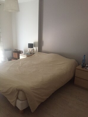 Ein Schlafzimmer mit Bett, Nachttisch, Lampe und einem Wandregal.