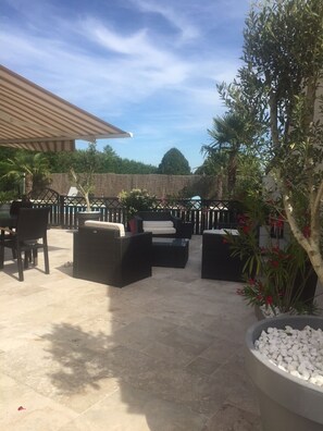 Ein Terrassenbereich im Freien mit Sitzgelegenheiten, einer Pergola und einer Zierpflanze.