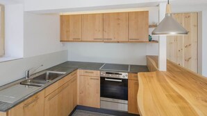 A modern kitchen with wooden cabinets, a stainless steel sink, a built-in oven, and a wooden countertop. - Guarda Val Müller Erlenstube Wohnung Erlenstube Wohnung Erlenstube by Interhome (Lantsch)
