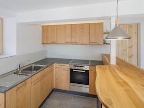 A modern kitchen with wooden cabinets, a stainless steel sink, a built-in oven, and a wooden countertop. - Guarda Val Müller Erlenstube Wohnung Erlenstube Wohnung Erlenstube by Interhome (Lantsch)