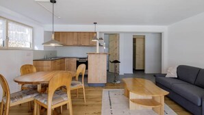 A modern living space with a dining area, a sofa, and a kitchen in the background. - Guarda Val Müller Erlenstube Wohnung Erlenstube Wohnung Erlenstube by Interhome (Lantsch)