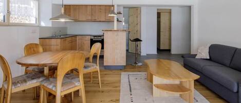 Un espacio habitable moderno con comedor, sofá y cocina al fondo.