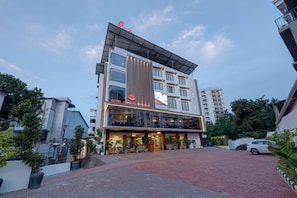 Un hotel moderno con un letrero llamativo, un acceso cubierto y un camino de entrada pavimentado.