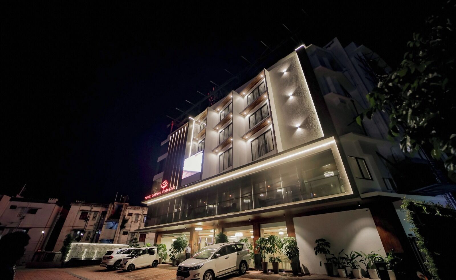 Un hotel con fachada moderna, varios balcones y una entrada bien iluminada.