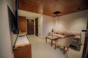 Una sala moderna con sofá, una mesa de centro y un televisor de pantalla plana montado en la pared.