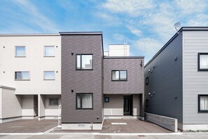 Un edificio residencial moderno de varios pisos con techo plano, múltiples ventanas y una antena parabólica.