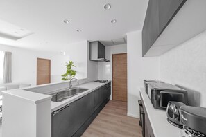 A modern kitchen with a central island, built-in appliances, and a minimalist design. - THE LUXERA  (Sapporoshi)