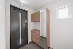 A hallway with a dark door, a wooden cabinet, and a window with blinds. - THE LUXERA  (Sapporoshi)
