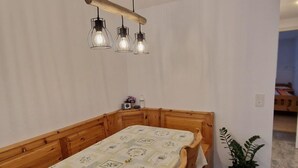 Ein Essbereich mit Holztisch und -stühlen, einer Pendelleuchte und einem Blumentopf.