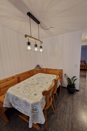 Ein Essbereich mit Holztisch und -stühlen, einer Pendelleuchte und einem Blumentopf.