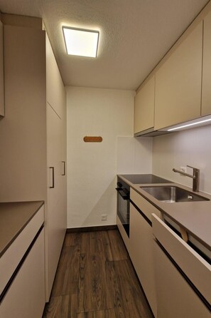 A compact kitchen with a built-in oven, a sink, and cabinets.
