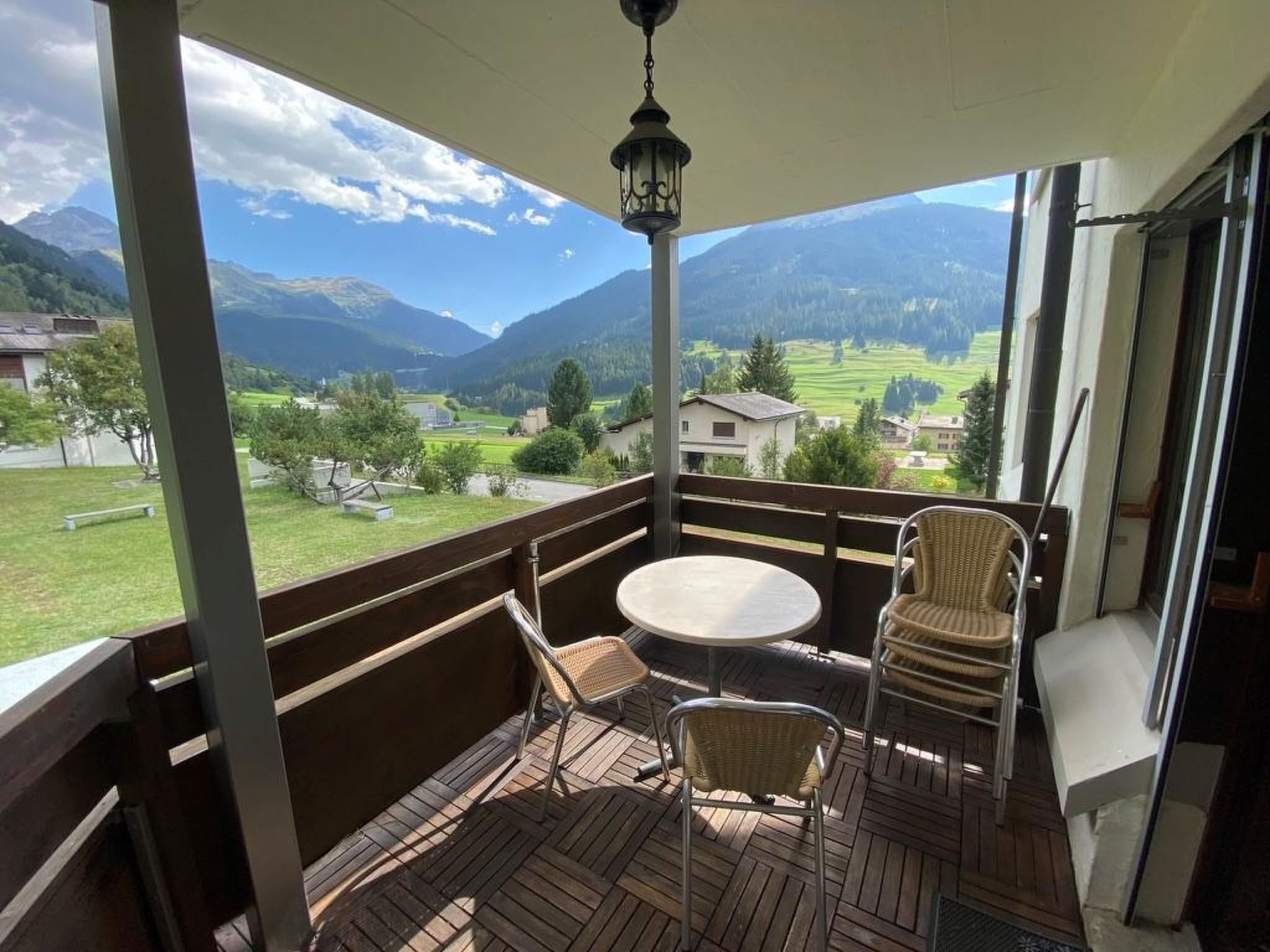 Ein Balkon mit Tisch und Stühlen, mit Blick auf eine Berglandschaft.