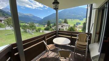 Ein Balkon mit Tisch und Stühlen, mit Blick auf eine Berglandschaft.