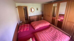 A bedroom with two beds, a wardrobe, a mirror, and a ceiling light. - Casa Surselva Whg Marti Appartement/Fewo, Bad, WC, 2 Schlafräume by Interhome (Savognin)