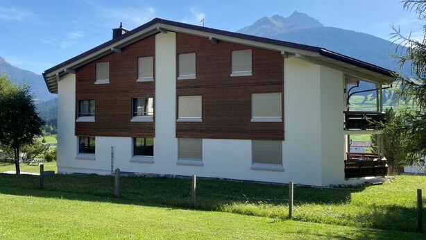 A two-story building with a flat roof, large windows, and a wooden facade. - Casa Surselva Whg Marti Appartement/Fewo, Bad, WC, 2 Schlafräume by Interhome (Savognin)