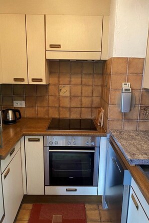 Una cocina compacta con horno integrado, fogones y microondas.