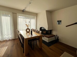 A dining area with a wooden table and chairs, a vase with dried plants, and a fireplace. - Tga Crap Alv Appartement/Fewo, Dusche, WC, 2 Schlafräume by Interhome (Savognin)