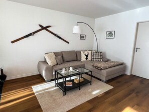 A living room with a sofa, a glass coffee table, a lamp, and a mounted axe. - Tga Crap Alv Appartement/Fewo, Dusche, WC, 2 Schlafräume by Interhome (Savognin)