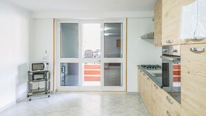 A kitchen with a microwave on a cart, a stove, and a sliding glass door leading to a balcony. - EmyHouse54 - Small Villa with Pool (Martina franca)